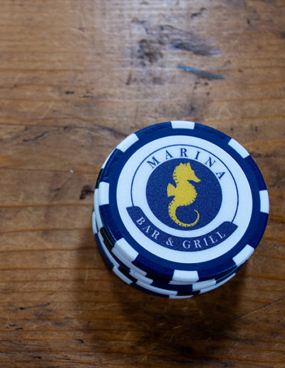 a stack of blue poker chips with Marina Bar & Grill blue and yellow logo