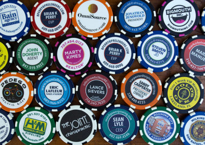 assorted poker chips with logos and business card designs